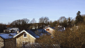 Vanha Malmi kuuluu Museoviraston valtakunnallisesti merkittävien rakennusperintökohteiden luetteloon. Puutalojen kattoja, taustalla kirkon torni, puissa ei lehtiä, kuva otettu talvella.