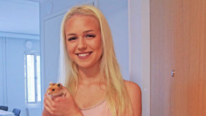 Aino Kiuru med sin hamster Nöpö hälsar sina nya grannar välkomna på saft en ung flicka med en hamster i famnen