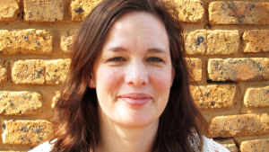 Britta Holmberg är vice generalsekreterare på World Childhood Foundation. britta holmberg står framför en tegelvägg. Hon bär en vit kofta.