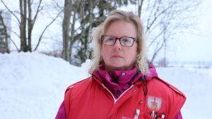 Ulrika Enqvist En kvinna med glasögon och axellångt blont hår står utomhus vid en snöhög. På sig har hon en röd Röda Korset-väst.