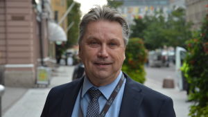 Fredrik Lindström. Porträtt på Fredrik Lindström med stadsmiljö i bakgrunden.