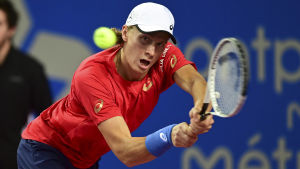 Emil Ruusuvuori. Emil Ruusuvuori böjer sig för att träffa en tennisboll.