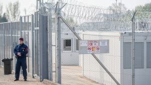 Strängt bevakade containrar har använts som logi i de strängt bevakade transitzonerna. Arkivbilden är från en av transitzonerna, den finns i närheten av den ungerska staden Tompa. Containrar som används för logi i en ungersk transitzon på gränsen mellan Ungern och Serbien. Området är omgärdat av ett stängsel och taggtråd, en vakt står utanför området. Fotot från ett läger nära den ungerska staden Tompa, den 6 april 2017.