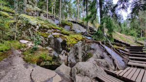 I bergsbranten finns totalt 20 jättegrytor i varierande storlek. Trappor bredvid en urholkning i ett berg.