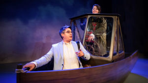 Jerry Wahlforss och Daniela Franzell i föreställningen "Hemåt över isen". En kvinna styr och en man sitter i en båt på en teaterscen.