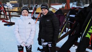 Theresia Johansson och Rebecca Nyberg är vana skidåkare. Två flickor står framför en ställning med skidor.