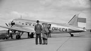 När den här bilden togs år 1947 var Malms flygplats huvudflygplatsen i Helsingfors. Helsingfors-Vanda öppnade 1952. Två män som står framför ett flygplan på Malms flygfält 1947.