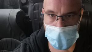 Pontus Johansson säger att hans arbetsresor blir mycket längre på grund av veckorna i karantän. En man med munskydd sitter i en buss.