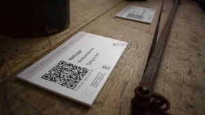 QR-koderna är enkla att använda även för en ovan. En lapp med en pixlad qr-kod för mobiler på ett gammalt träbord.