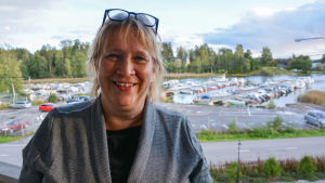 Clara Lindqvist bor på Simsalö och jobbar på fastlandet. Hon skulle gärna åka med förbindelsebåt direkt från Simsalö till Pörtö. Kvinna i grått, bakom syns småbåtshamn i Gumbostrand