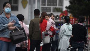 Föräldrar stod utanför en skola i staden Tongliao i Inre Mongoliet förra veckan. Det finns ytterst få bilder och videor från protesterna i Inre Mongoliet. Internetcensuren i Kina är effektiv och utländska journalister övervakas strängt om de lyckas ta sig till provinsen. Människor med munskydd står på gatan utanför en skola.