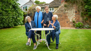 Neljä aateloitua brittinäyttelijätärtä istuu puutarhassa ja nauraa.