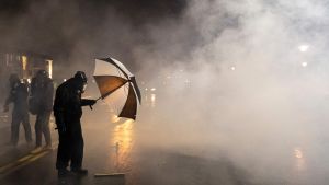 En demonstrant utanför polisstationen i Brooklyn Center skyddar sig mot polisens tårgas sent på måndag kväll, lokal tid. En demonstrant utanför polisstationen i Brooklyn Center skyddar sig mot polisens tårgas sent på måndag kväll, lokal tid.