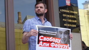 En demonstration i Moskva mot utvisningen av Ali Feruz En man som demonstrerar håller upp ett plakat med Ali Feruz bild