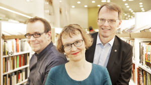 Aapo Reselius, Annvi Gardberg och Anders Gardberg. Aapo Reselius, Annvi Gardberg och Anders Gardberg mellan bokshyllor.