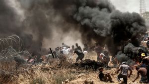 FN och omvärlden oroar sig för vad som kommer att hända efter massakern i Gaza på måndag Palestinier i närheten av gränsstängslet mellan Gazaremsan och Israel bland rökbomber, barn i förgrunden.