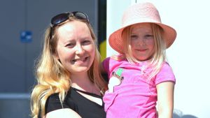 Marika Mustakangas med sin dotter. Närbild, porträtt, av Marika Mustakangas, en ljus, långhårig kvinna med svart t-skjorta, och hennes dotter med solhatt och rosa t-skjorta.