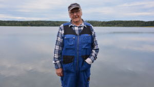 Dragsfjärden är vacker och värd att fortsätta kämpa för, anser Tryggve Röblom. Tryggve Röblom i blå arbetsställ står på en brygga vid sjön Dragsfjärden med blicken in i kameran.