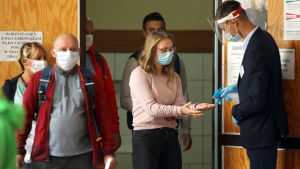 I vallokalerna kämpade man mot coronaviruset bland annat genom att desinficera väljarnas händer. Bilden är från Bukowina Tatrzańska. En man desinficerar en kvinnas händer med sprayflaska. Bakom kvinnan står andra människor på rad. Personerna ska rösta i Polens presidentval.