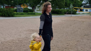 En kvinna och ett litet barn i gul jacka som tittar mot havet. 