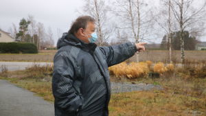 Ungefär här skulle vägen gå, visar Edd Grahn. Omfartsvägen skulle bli ungefär en kilometer lång och gå väster om simhallen. En man med munskydd pekar mot en åker.