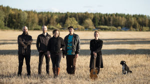 Désirée Saarela & Triskel + hund. 5 personers folkband står ute på en åker, hund är med.