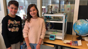 Oliver Ström och Linn Sievers är nöjda med hur teknologin utnyttjas i undervisningen. De står bredvid en 3D-printer som också används i skolan. Linn Sievers och Oliver Ström går i årskurs fem i Kottby lågstadieskola.