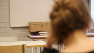De elever som har svårast att hålla fingrarna borta från sin mobil får lägga den i en skild låda. Mattliden koulun oppilas katsoo kännykkälaatikkoa