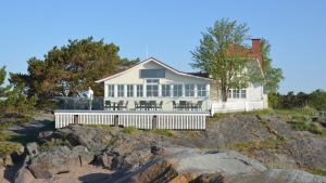 Fyra vindarnas hus har i de senaste åren drivits av Hangöföretagaren Kaj-Erik "Nixu" Knichter. En gammal vit trävilla med rött tak vid havet, på uteserveringen står en man.