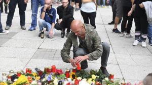 En man tänder ett ljus där en 35-årig man knivhöggs till döds under söndagen. En man tänder ett ljus där en 53-årig man knivhöggs under söndagen.