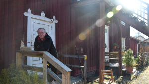 Jorma Massinen bor i en av de gamla bruksbostäderna. Han är engagerad i natur och miljö och tycker att plastavfallskärlen är viktiga. man på förstukvist till gammalt hus
