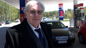 Riki Grahne tycker att trafiken i Finland är bättre än i Portugal. Man står framför bil vid bensinstation.