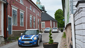 Pekkala och Kantola hoppas på att det ska komma fler blommor i krukorna. Kullerstensgata i Borgå med livlig trafik.