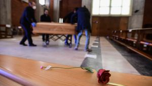 Offren begravdes snabbt och de anhöriga fick ingen möjlighet att ta avsked En ros ligger på en kista i en kyrka i norra Italien. I bakgrunden förs ytterligare en kista in i kyrkan