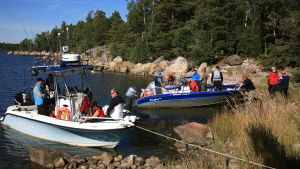 Så här kan en solig semesterdag tillbringas. Två båtar vid land som är fullproppade med människor i båtarna. Det är en solig sommardag.