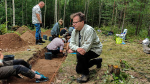 Jan Fast leder ofta utgrävningar där både amatörarkeologer och skolklasser deltar. En man sitter på huk nere vid ett sanddike.
