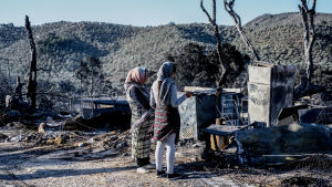 Två kvinnor tittar på spåren efter branden i lägret Moria. Migranter tittar på spåren efter branden i lägret Moria