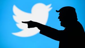 Trumps Twitterkonto har stängts för gott. I bakgrunden syns Twitters logo – en vit fågel med ljusblå bakgrund. I förgrunden syns en siluett av Donald Trump som pekar åt sidan.