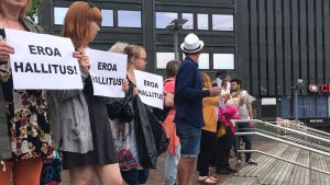 Demonstranter står uppradade på Salomonsgatan i Helsingfors. Demonstranterna står med skyltar som kräver regeringens avgång.