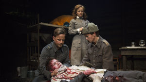 Arvid på dödsbädden. Alex Holmlund omringad av Peter Kanerva, Sanna Majuri och Linda Zilliacus. Foto från Vinterkriget - here we go again på Lilla Teatern.