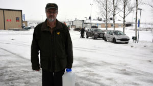 Hannu Pajala utanför brandstationen i Nousis. Hannu Pajala håller i sin vattendunk.