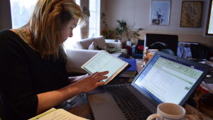 Lea Räisänen har vänt på många papper innan hon fått grepp om kommunens budget. Lea Räisänen sitter vid datorn och läser ur boksluten.