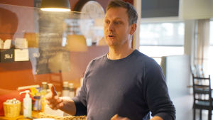 Luncherna har gått ner med 25 procent jämfört med hur det var före coronaviruset. Ulf Wadenström misstänker att antalet lunchgäster aldrig kommer att återgå till tidigare proportioner efter att läget normaliseras. Samhället har förändrats, menar Wadenström och syftar bland annat på att det finns de som kommer att fortsätta jobba på distans och äta hemma, åtminstone delvis. En man står och gestikulerar med armarna samtidigt som han pratar inne i en tom restaurang.