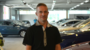 Jani Haavisto säljer bilar på Auto Lähdemäki i Vasa. jani haavisto står i en blå piketröja i en bilhall