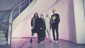 Ruusuista povataan suomalaisen popmusiikin mullistajaa. Ruusut-yhtye vaaleanpunaisen taustan edessä.