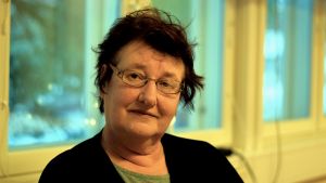 Bildningsnämndens ordförande Maj-Britt Malmén säger att det är mycket som måste tas i beaktande när det gäller skoltransport. Kvinna med mörkt hår och glasögon ser mot kameran. Ett fönster i bakgrunden.