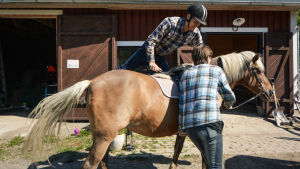 André Norrgård hoppar säkert upp på den estniska D-ponnyn Laasi. En man tar sig upp på en hästrygg.