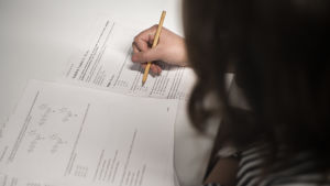 Flera inträdesprov, bland annat det massiva högskoleprovet i Sverige, inhiberas. En kvinna skriver ett inträdesprov. Man ser inte kvinnans ansikte.
