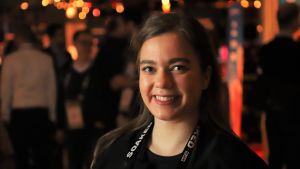 Jessica Blechingberg trodde aldrig hon skulle jobba med teknologi, men hennes första Slush inspirerade henne att satsa på branschen. En ung dam i svarta kläder ler mot kameran.