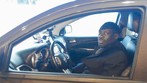 Ahmed Bonaparte är noggrann med att desinficera bilen efter varje passagerare. En man sitter i en taxibil. Han tittar in i kameran genom fönstret